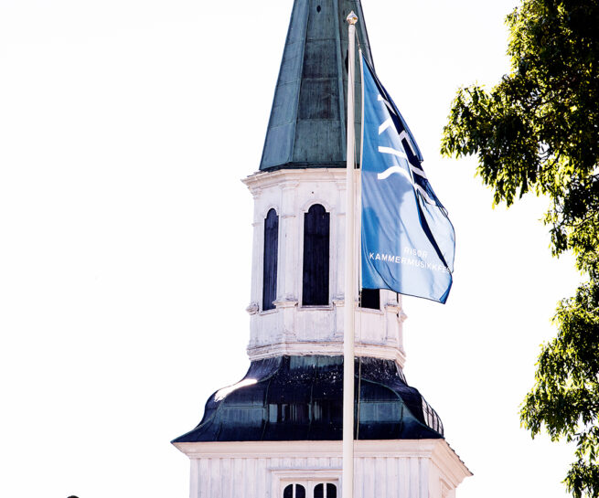 Risør kirke med Risør kammermusikkfest-flagg vaiende foran