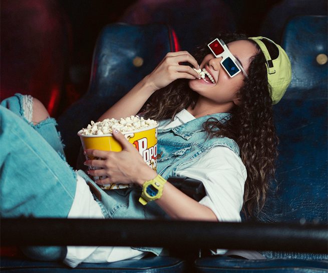 Jente med popcorn i kinosal